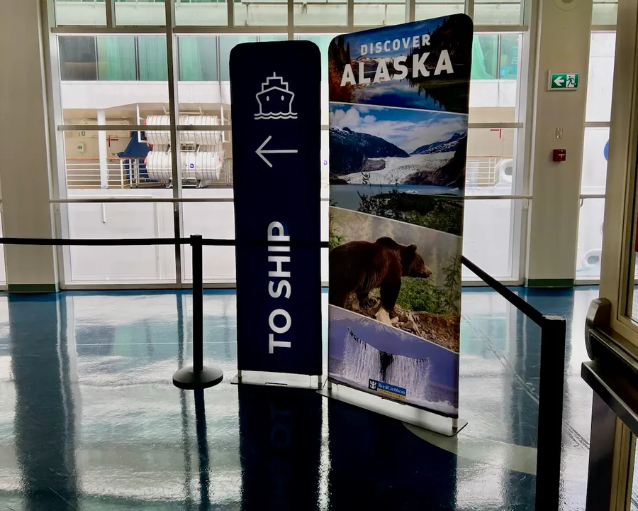 Two signs: one indicating the way towards the ship and the second advertising excursions in Alaska