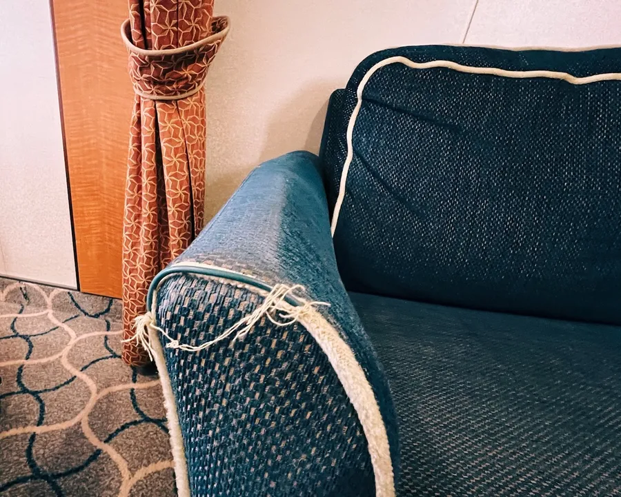 A navy blue sofa arm showing fraying along the edges