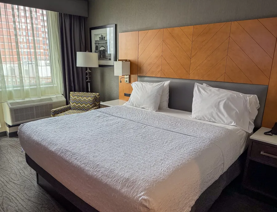 King bed with wooden headboard in a Brooklyn Hampton Inn hotel room