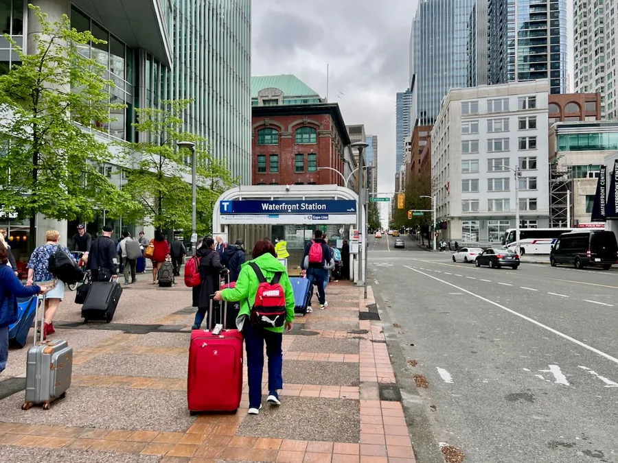 People dragging luggage towards the Skytrain in Vancouver