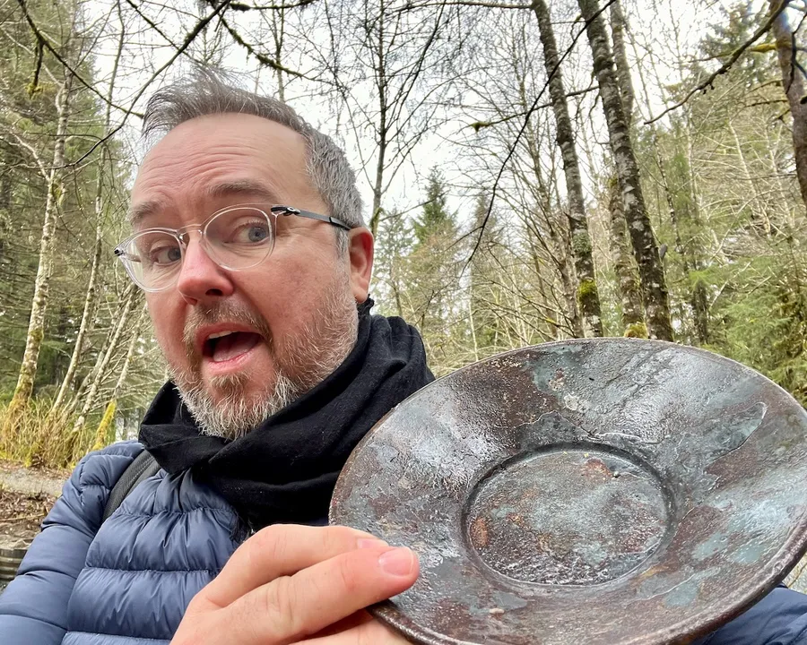 A man holds up an empty gold pan