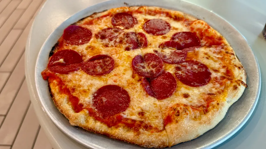 A small peperoni pizza on a metal tray 