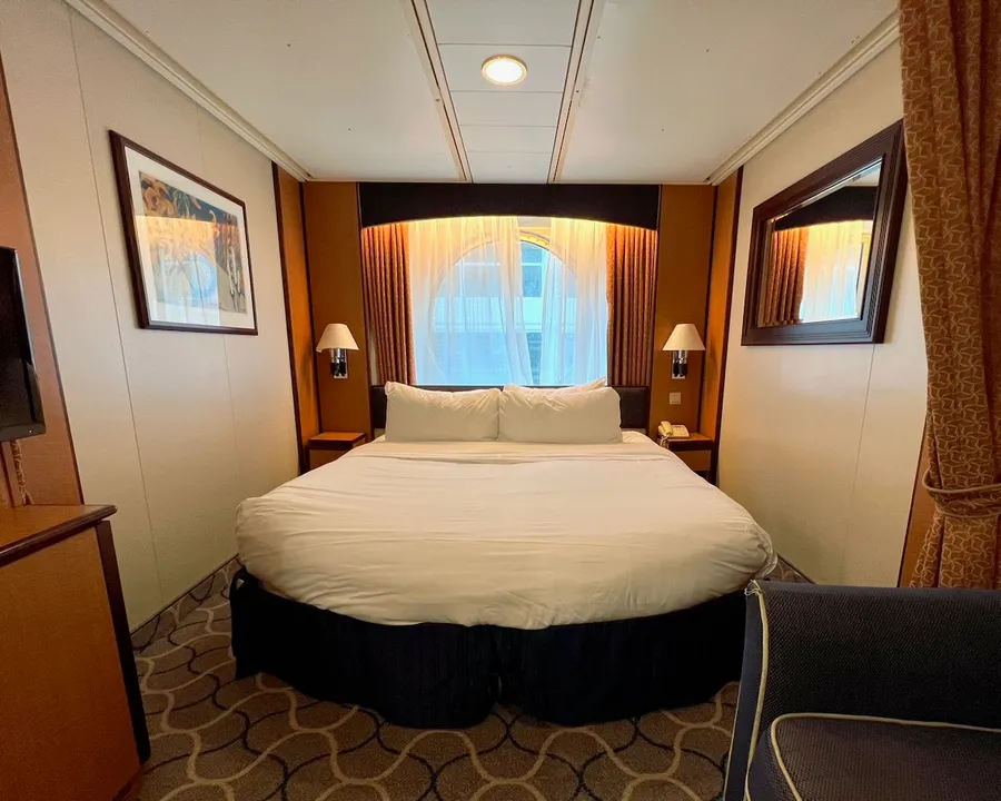 Ocean View room interior on Brilliance of the Seas, showing a double bed and port hole