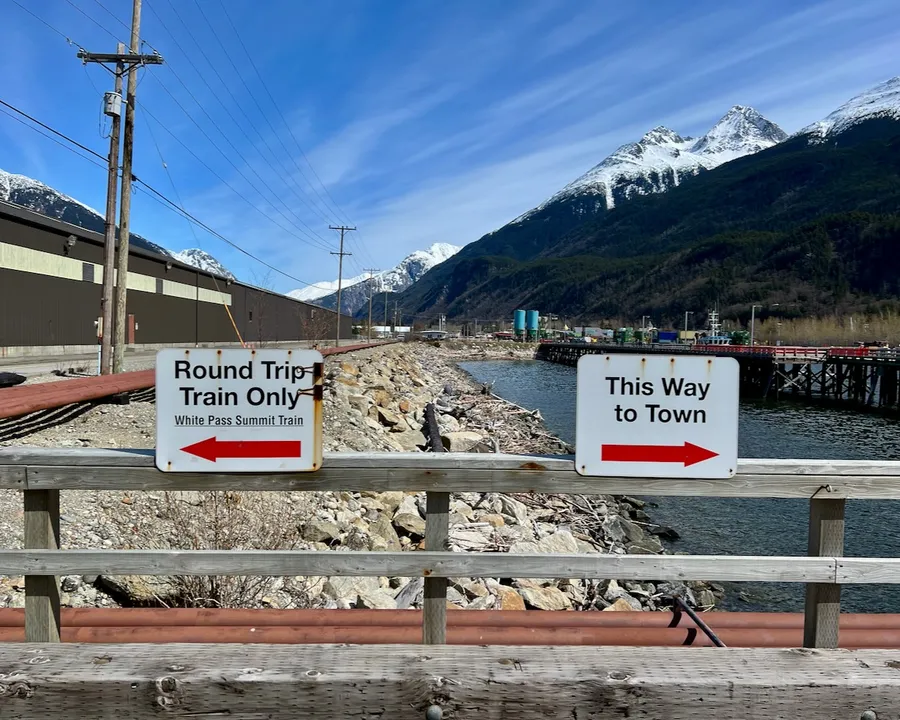 Two signs on a bridge in Skagway, one to White Pass railcards and the other to downtown